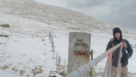 man hiking and opening gate in the faroe islands in winter