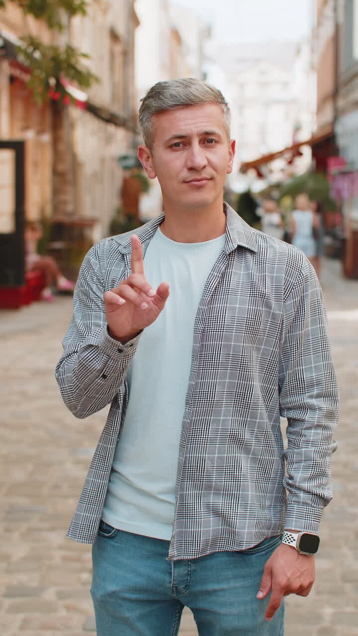 Upset man reacting to unpleasant awful idea wave hand shake head no while standing on city street