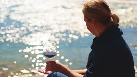 woman enjoying a glass of red wine by the water