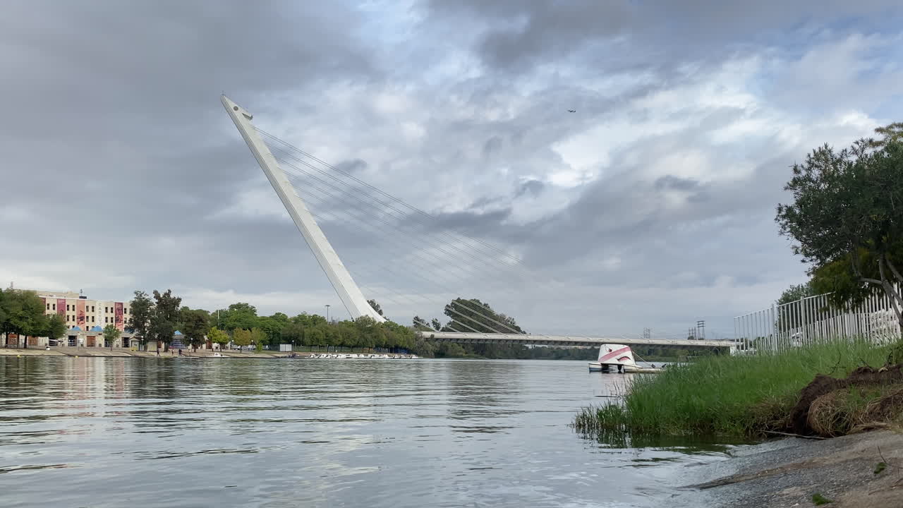 Vista distante di un lungo fiume con canottieri che si allenano sotto due ponti moderni in una giornata limpida e luminosa