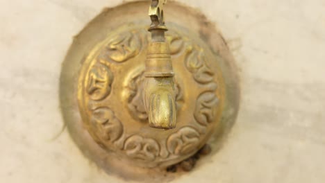 close-up of an ornate brass faucet dripping water on a stone wall