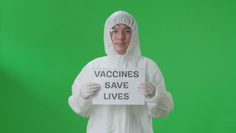 asian man wearing personal protective equipment uniform ppe and holding vaccines save lives sign in the green screen studio