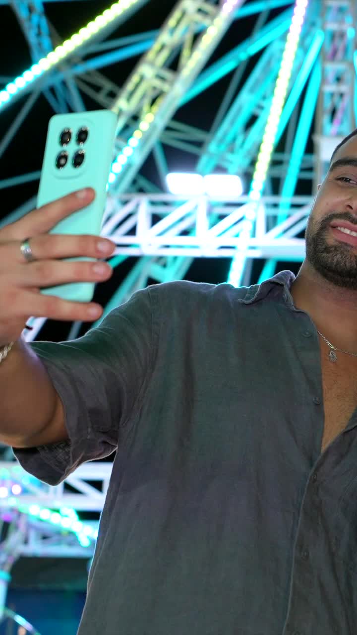 Couple taking a selfie at a fair in front of a Ferris wheel