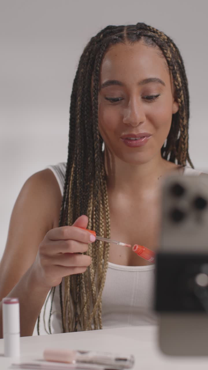 joven grabando belleza maquillaje revisión o tutorial para brillo de labios en teléfono móvil para cargar en el canal de redes sociales