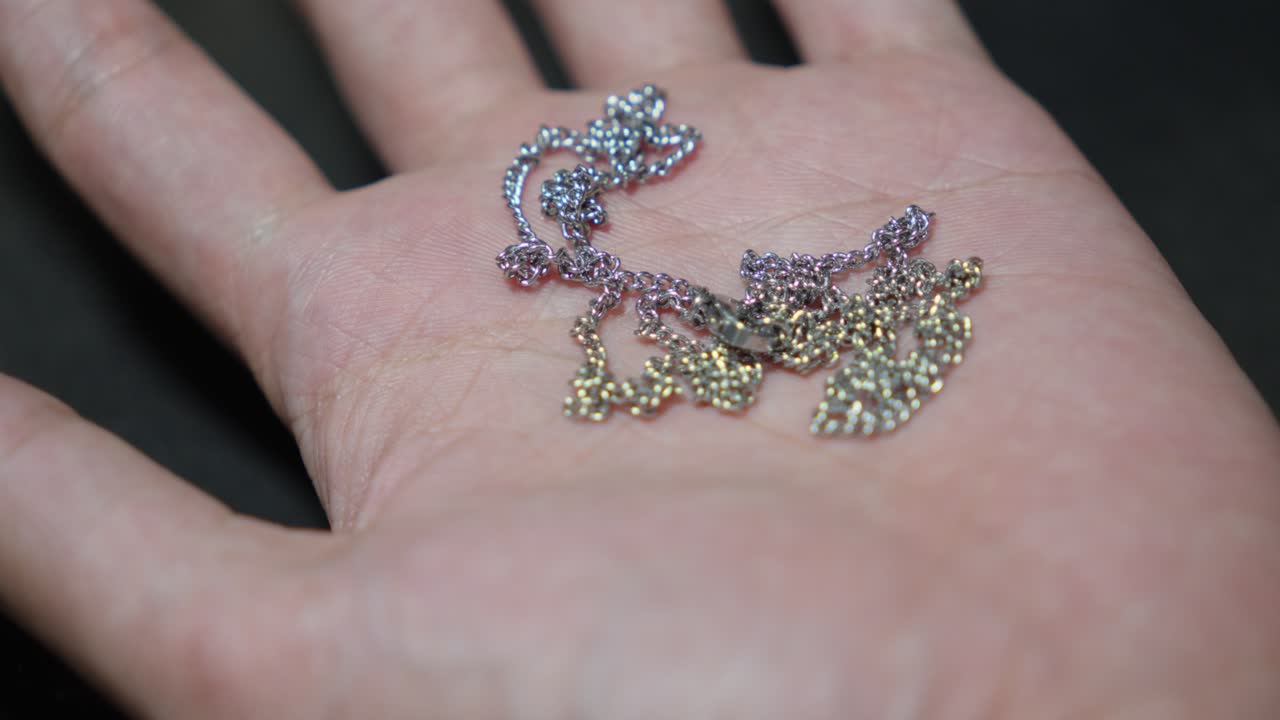 은색 사슬 목걸이를 손바닥에 붙여서 가까이 올려놓습니다.