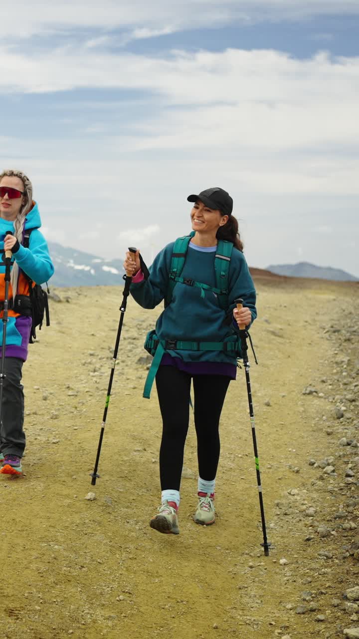 Donna felice che fa escursioni con bastoncini da trekking su un sentiero di montagna