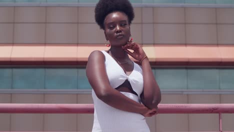 from a rooftop, a young black girl in a white dress surveys the city close up