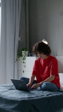 mujer trabajando en una computadora portátil en su dormitorio