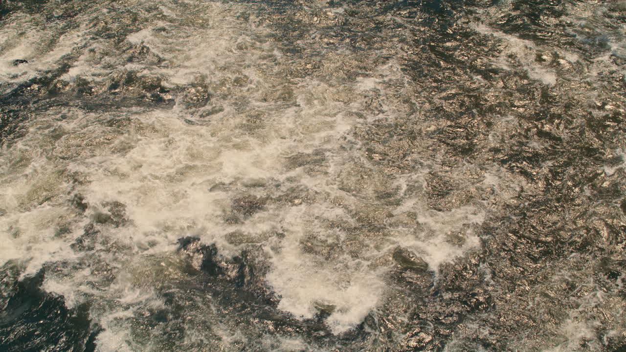 white river water flowing away from camera, aerial perspective, static shot, slow motion 40fps. Summer afternoon light