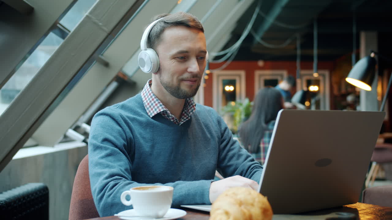 Mand arbejder på bærbar computer på café