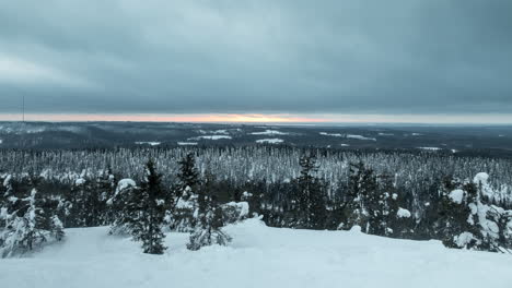 time lapse shot, of dark clouds moving over snow, covered trees, hills and nordic wilderness, sunset colors in the background, on a winter evening, in koli national park, north karelia, finland