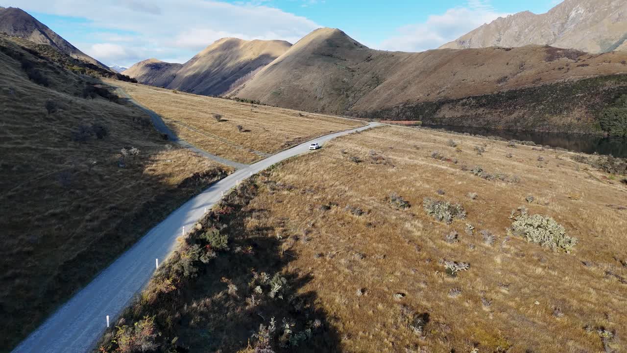 Aerial view of a winding road through mountainous terrain in New Zealand, showcasing natural beauty and serene environment