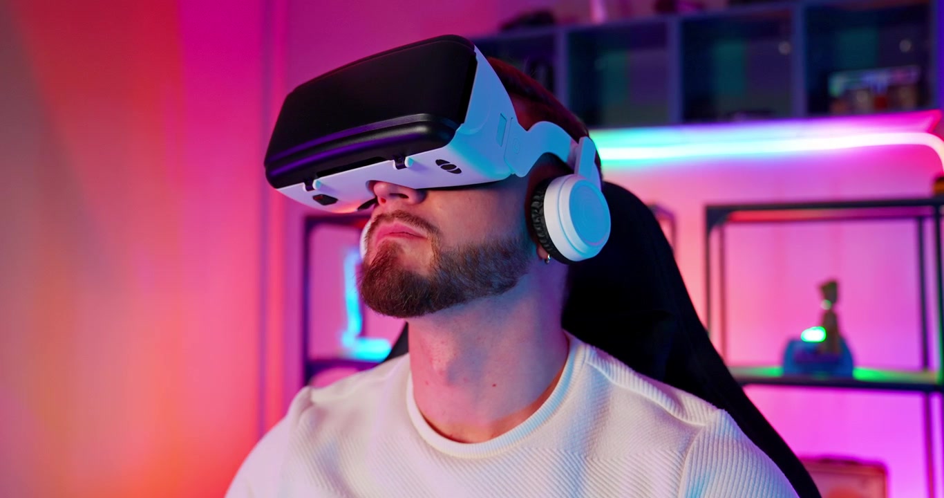 Giovane uomo che sperimenta la realtà virtuale con cuffie e luci al neon