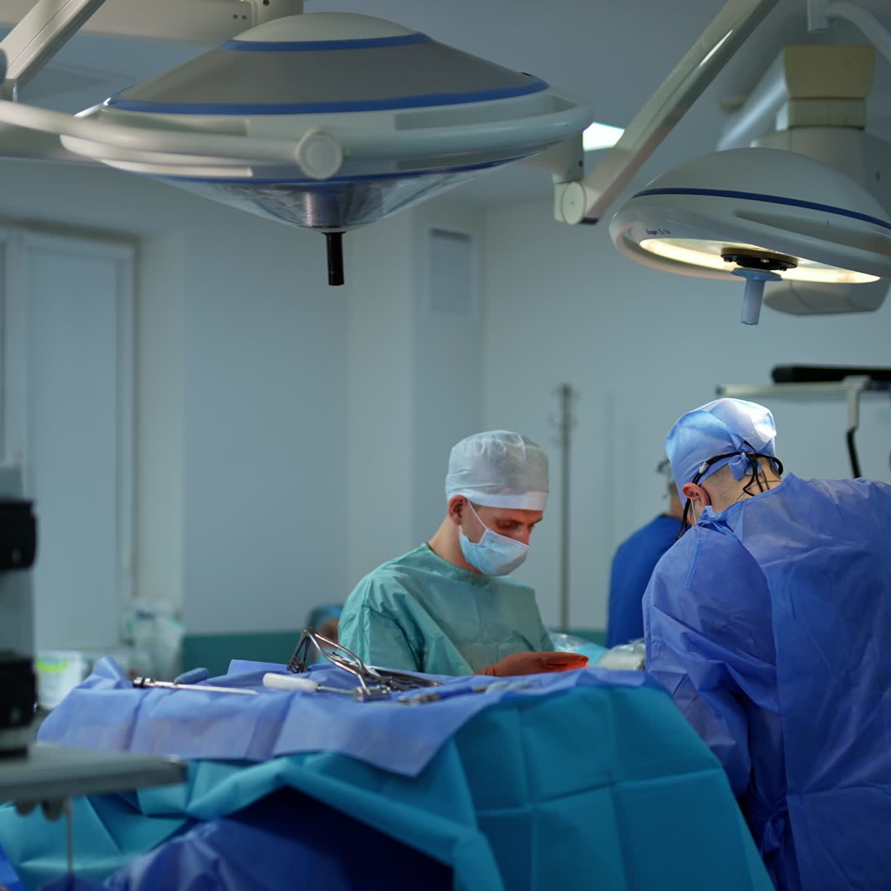 Conducting neurosurgery operation in modern clinic. Team of doctors working hard over the patient. Working screen at backdrop