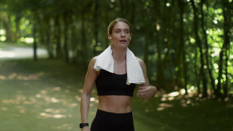 athletic woman running and cooling down in a park