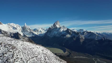 aerial footage of laguna torre in el chaltén, argentina. snow-covered fitz roy and cerro torre rise under a clear sky. a breathtaking patagonian panorama at summer’s end, captured in stunning 4k