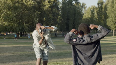 young black boy showing biceps while his father taking photo.