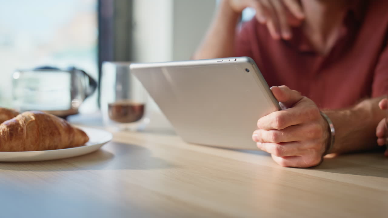 Joyful husband showing tablet to smiling wife sitting together at home closeup