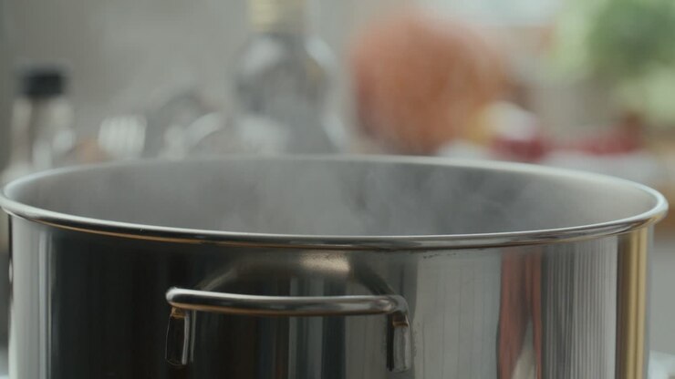 Hand Sprinkling Salt into Steaming Steel Pot during Cooking