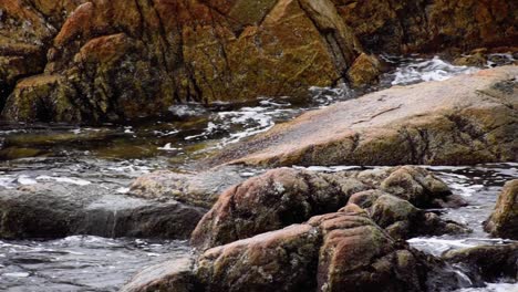 fast water hits bedrock on shoreline, slow motion medium shot