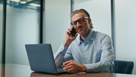 director sonriente llamando al teléfono en la oficina corporativa de primer plano. hombre de negocios hablando