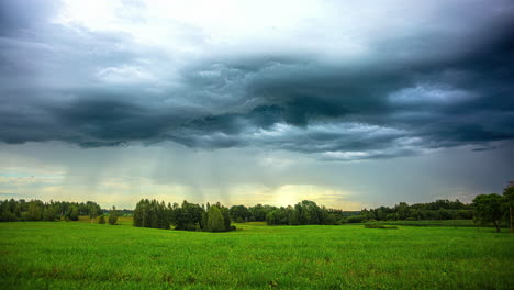 Timelapse-Del-Paisaje-De-Pradera-Verde,-Nubes-De-Lluvia-Tormentosas-Flotando-Sobre-Tierras-Rurales,-Ambiente-Cinematográfico-Idílico,-Salvapantallas-Nostálgico,-Crepúsculo-Amarillo-En-El-Horizonte