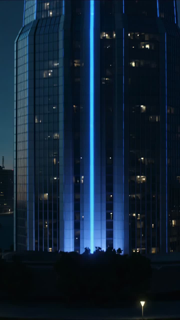 Vertical video: Tilting camera revealing tower at night, lighting blue LED and crown, showing lines
