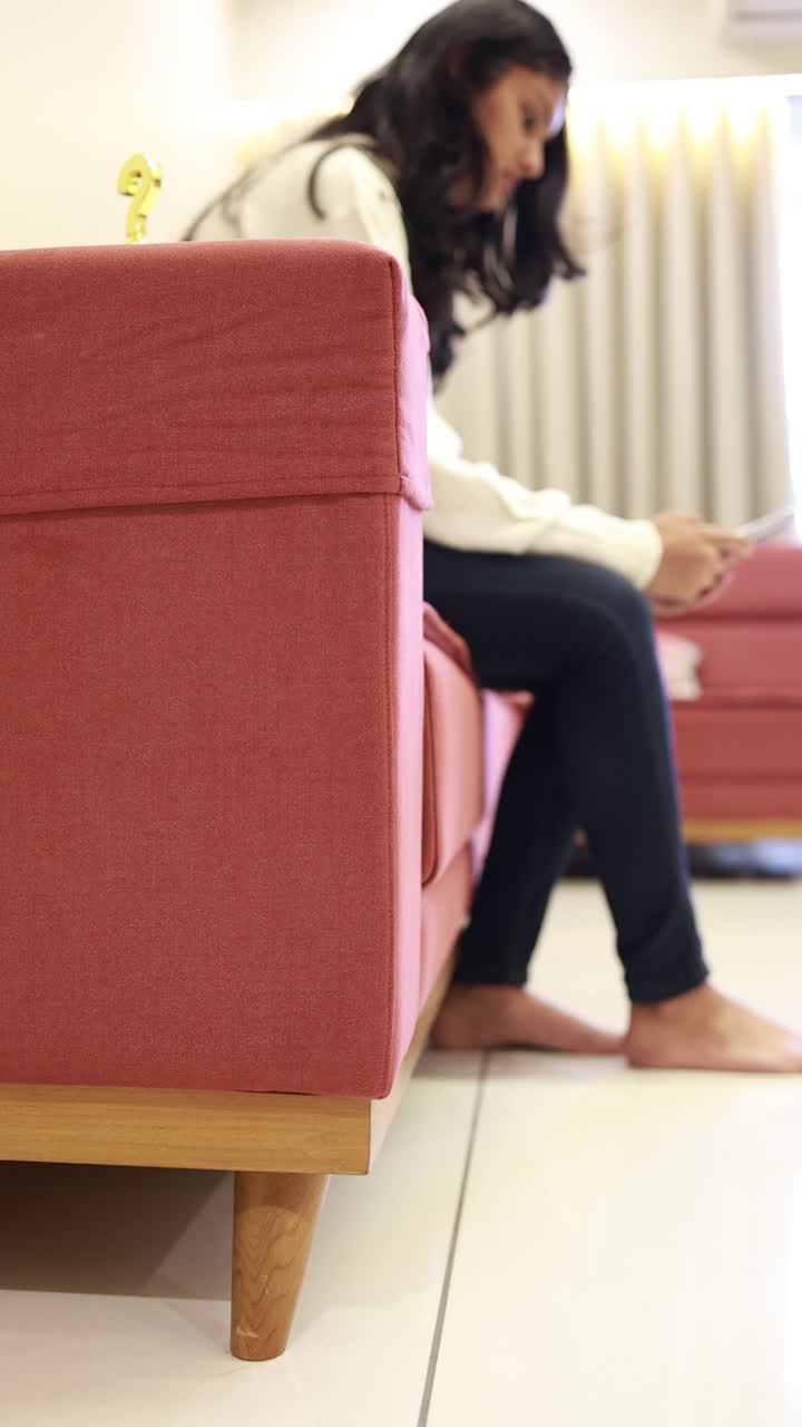 woman using a tablet and setting at pink sofa