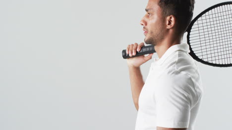 Young-biracial-man-poses-with-a-badminton-racket,-with-copy-space