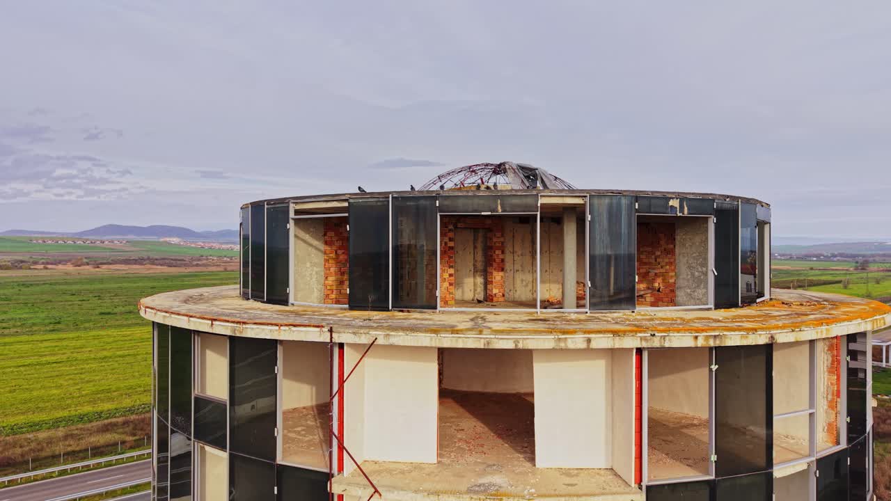Aerial view of an abandoned round building under a cloudy sky