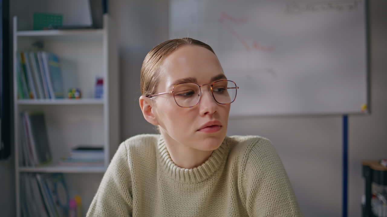 Lady tutor wearing glasses working at school closeup. Teacher looking distance