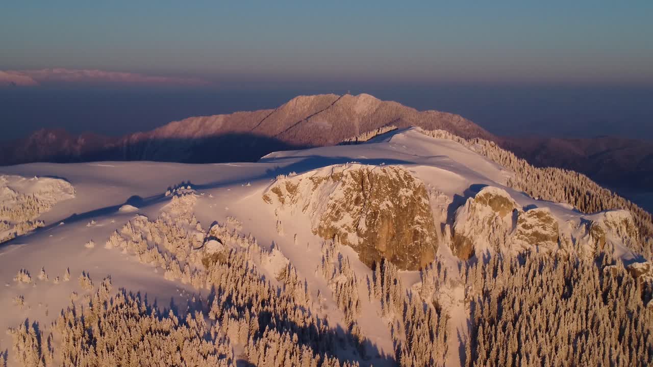 espectáculo de drones de invierno: sea testigo de la impresionante belleza de un pico de montaña cubierto de nieve al atardecer, capturado desde una perspectiva aérea