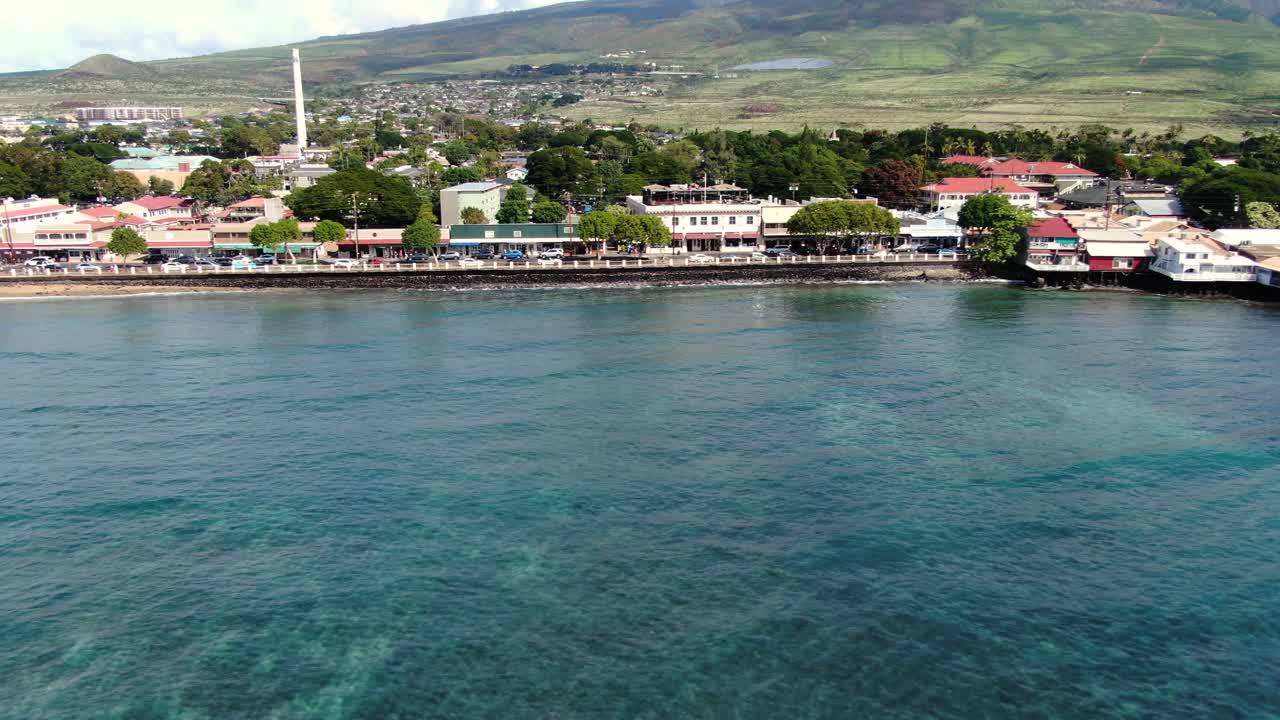 drone far away pan dall'altra parte della strada principale a lahaina maui lungo la costa blu dell'oceano