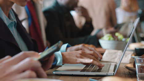 diverse business people working in cafe bustling with activity drinking coffee relaxing on lunch using technology in busy restaurant