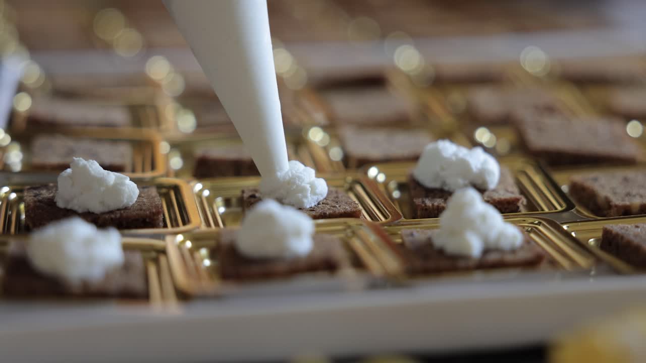 Catering finger food being prepared by chef placing cream on delicious food