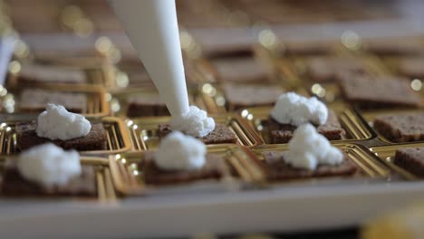 catering finger food being prepared by chef placing cream on delicious food