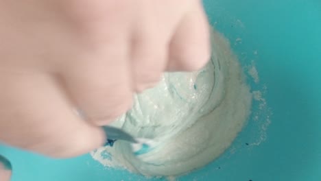 mezcla de colorante alimentario azul a la mezcla de masa de bizcocho vista de arriba hacia abajo