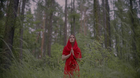 Mujer-Vestida-De-Rojo-Rezando-En-El-Bosque