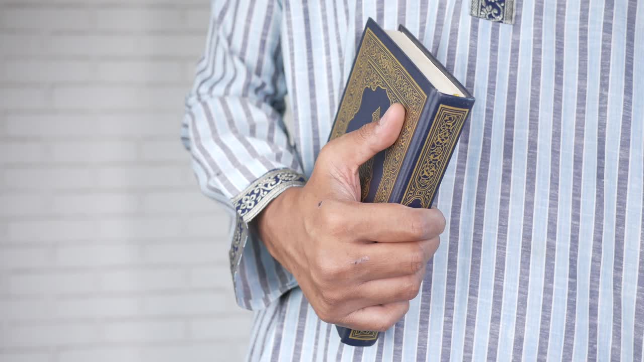 모슬림 남자의 손은 복사 공간과 함께 거룩한 책 쿠란을 들고 있습니다.