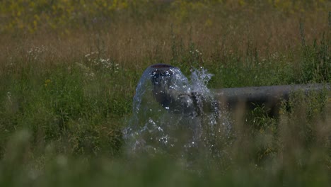 Water-Bursting-out-of-Pipe-on-a-Field---SLOMO---RACK-FOCUS