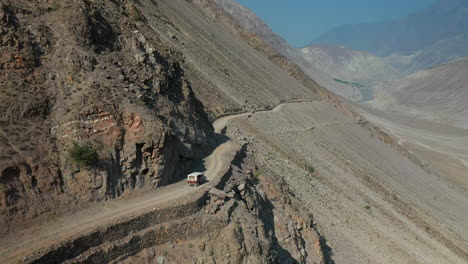 Drone-shot-of-vehicle-on-Fairy-Meadows-Road-in-Pakistan,-second-deadliest-highway-in-the-world,-wide-aerial-shot