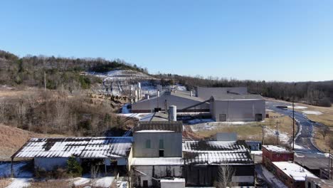 aerial drone footage dollying towards an abandoned, decaying brick factory on the edge of a quarry and forest