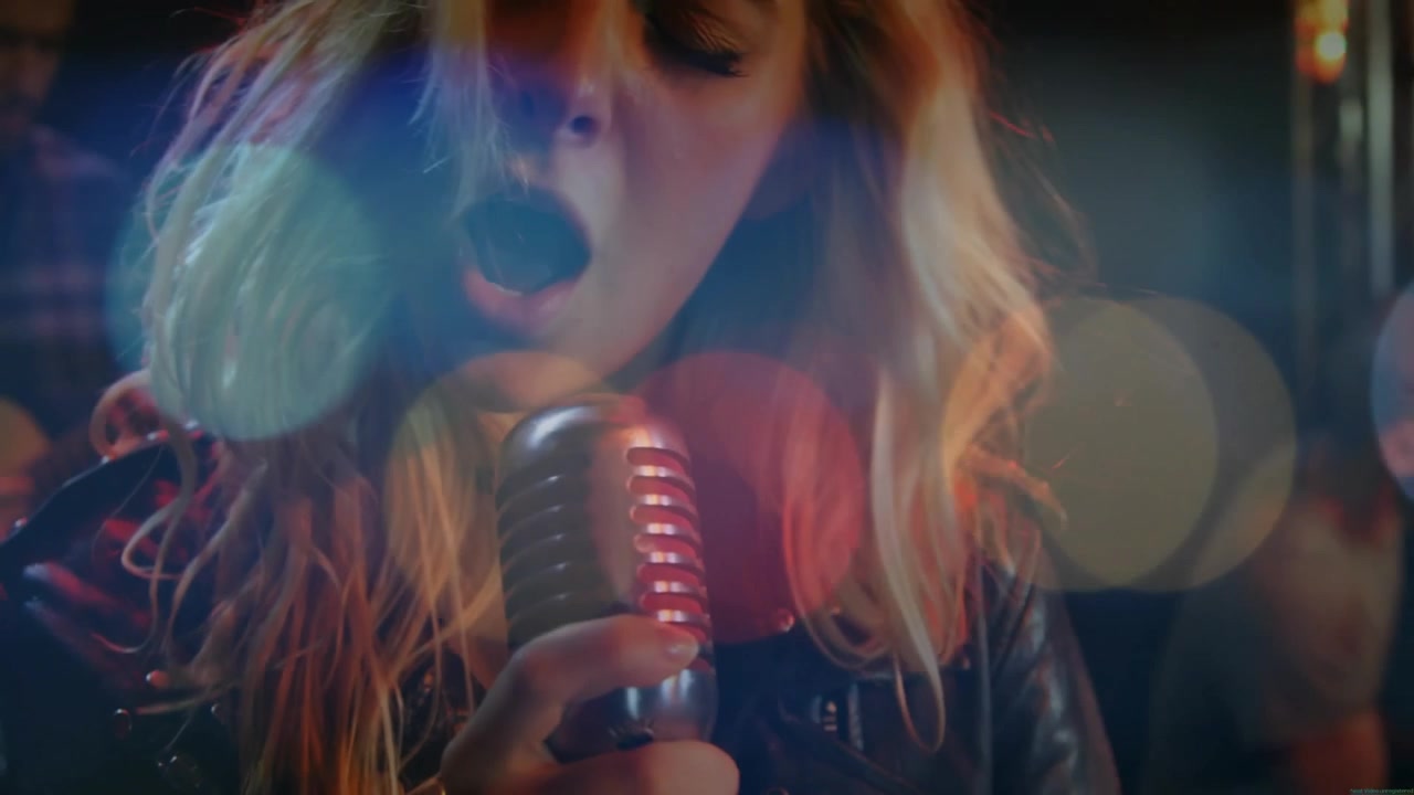Female singer adjusting mic, starting melody with lens flares and guitarist strumming during music