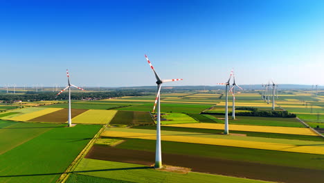 turbines produce energy in fields. turbines spin under a clear blue sky, transforming wind into renewable energy across green fields