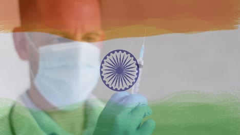 Composition-of-covid-19-cells-and-male-doctor-with-face-mask-and-vaccine-over-indian-flag