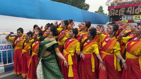 group of ladies dressed in yellow bengali traditional saree rehearsing before the performance at red road for durga puja procession in kolkata, india.