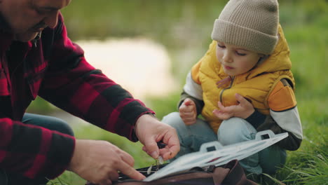 old-fisherman-is-choosing-fishing-gear-little-boy-is-spending-time-with-grandpa-in-nature