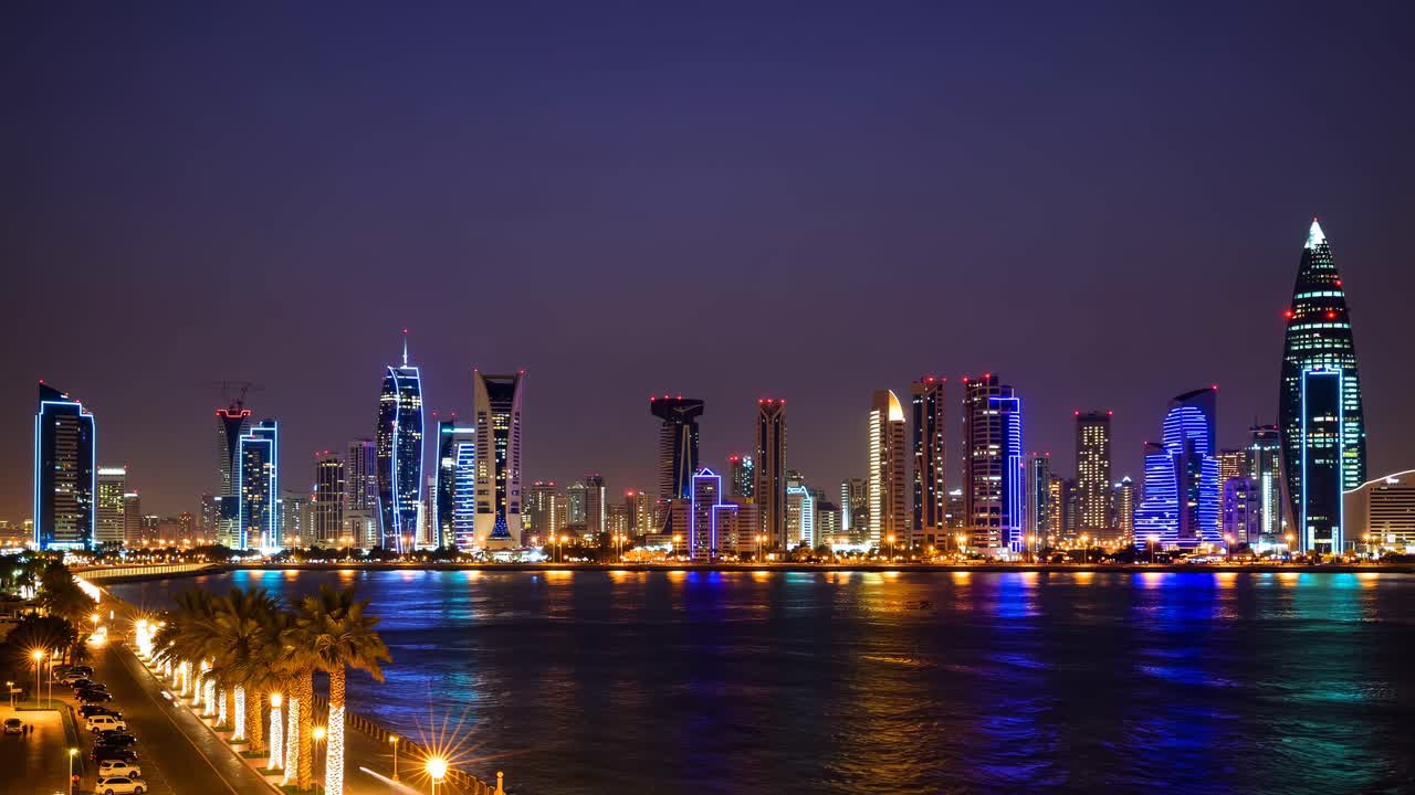 Aerial view of a vibrant city skyline at night, with illuminated skyscrapers reflecting
