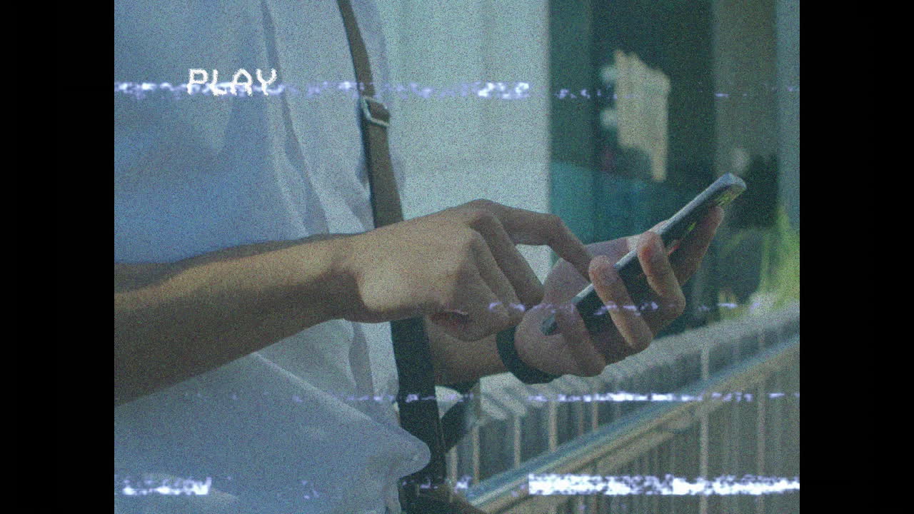 Using smartphone, person viewing animation with static lines and PLAY text overlay