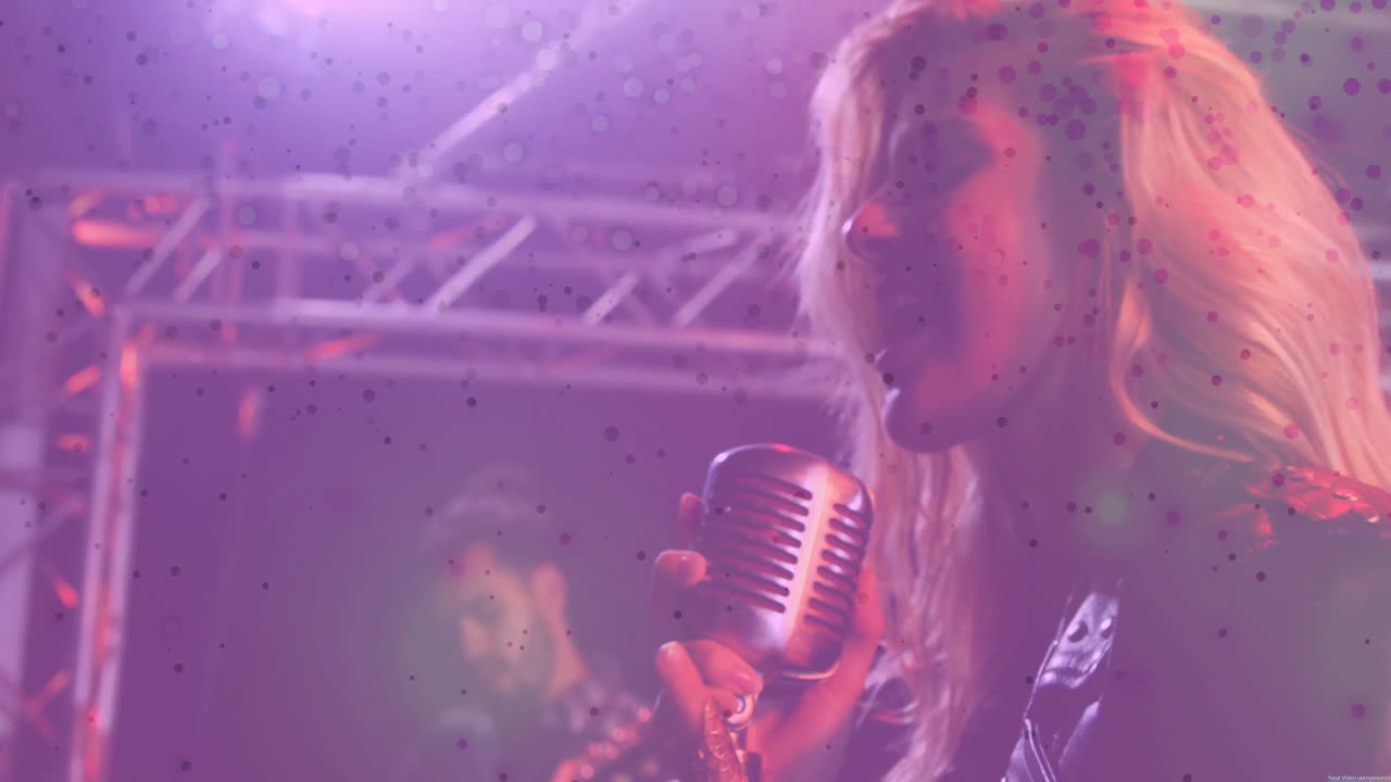 Cantante e musicista donna che si esibiscono in un concerto, con icona di microfono animata e raggi di luce.